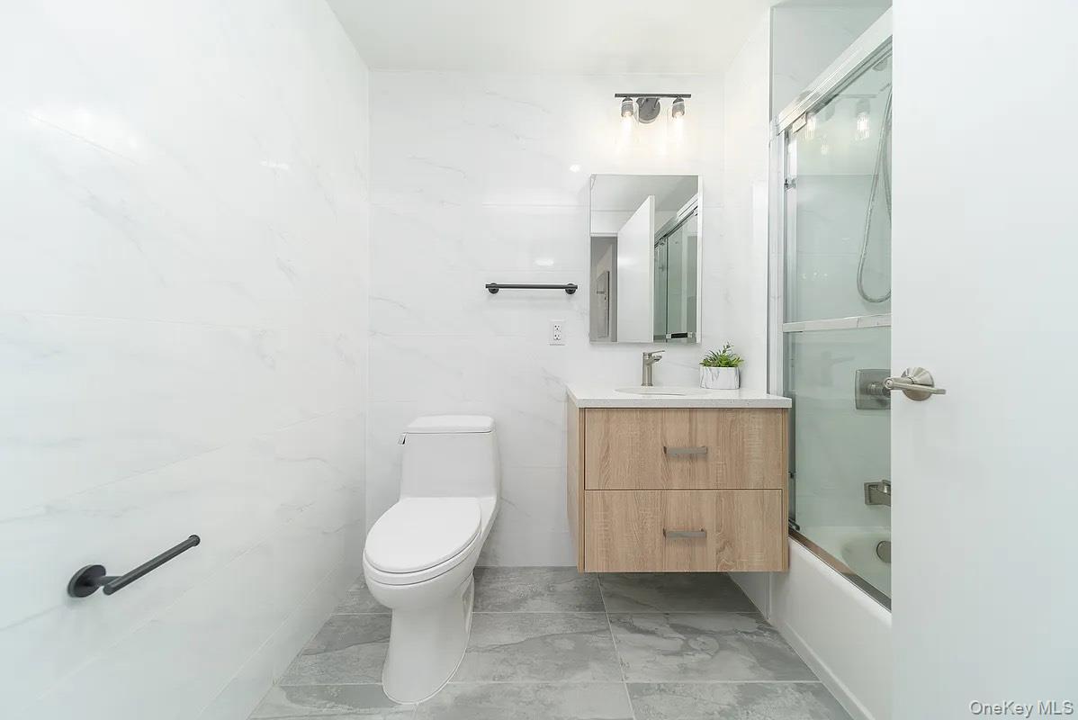 131-19 Fowler Avenue, Unit 4A Queens, NY 11355 - Photo 7 of 8 a bathroom with a granite countertop sink toilet and shower