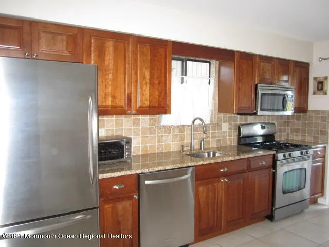 a kitchen with stainless steel appliances granite countertop a stove a sink and a refrigerator