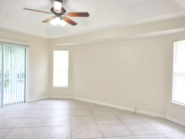 a view of an empty room with a window and chandelier fan