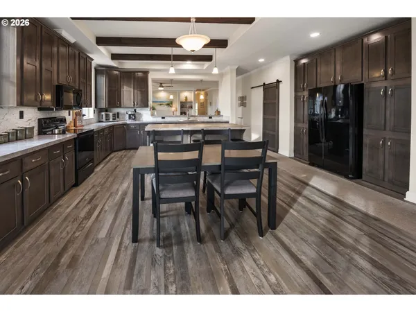 a kitchen with stainless steel appliances kitchen island granite countertop a table chairs sink and cabinets