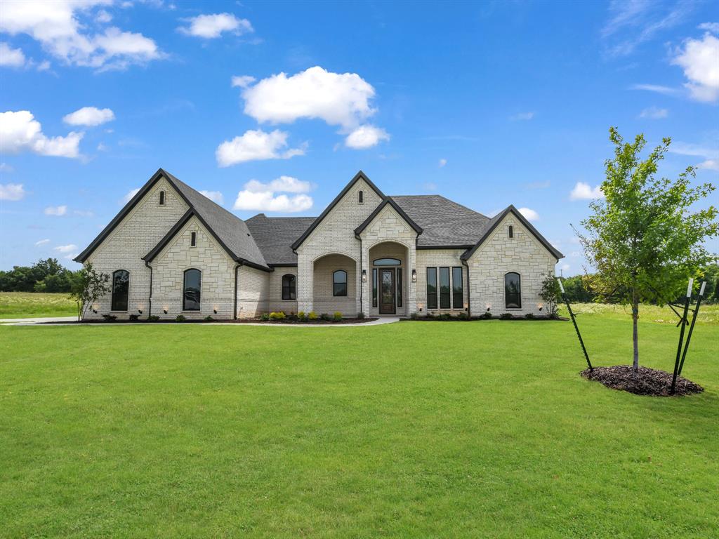 Traditional house with a front yard, stone siding, and a shingled roof