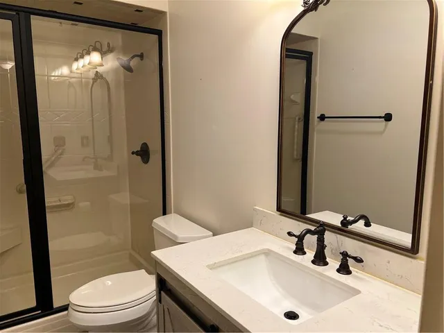 a bathroom with a granite countertop sink toilet and shower a mirror