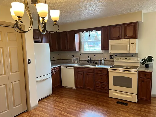 a kitchen with stainless steel appliances granite countertop a refrigerator a stove a sink and a dining table with wooden floor