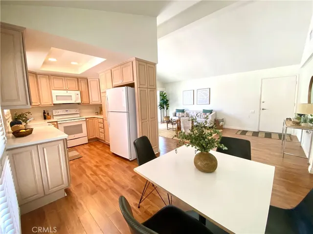 a kitchen with a refrigerator a stove and a dining table with wooden floor