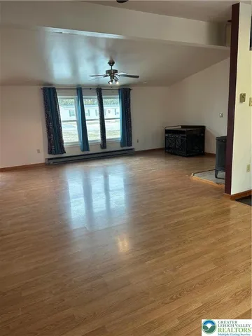 a view of an empty room with window and wooden floor