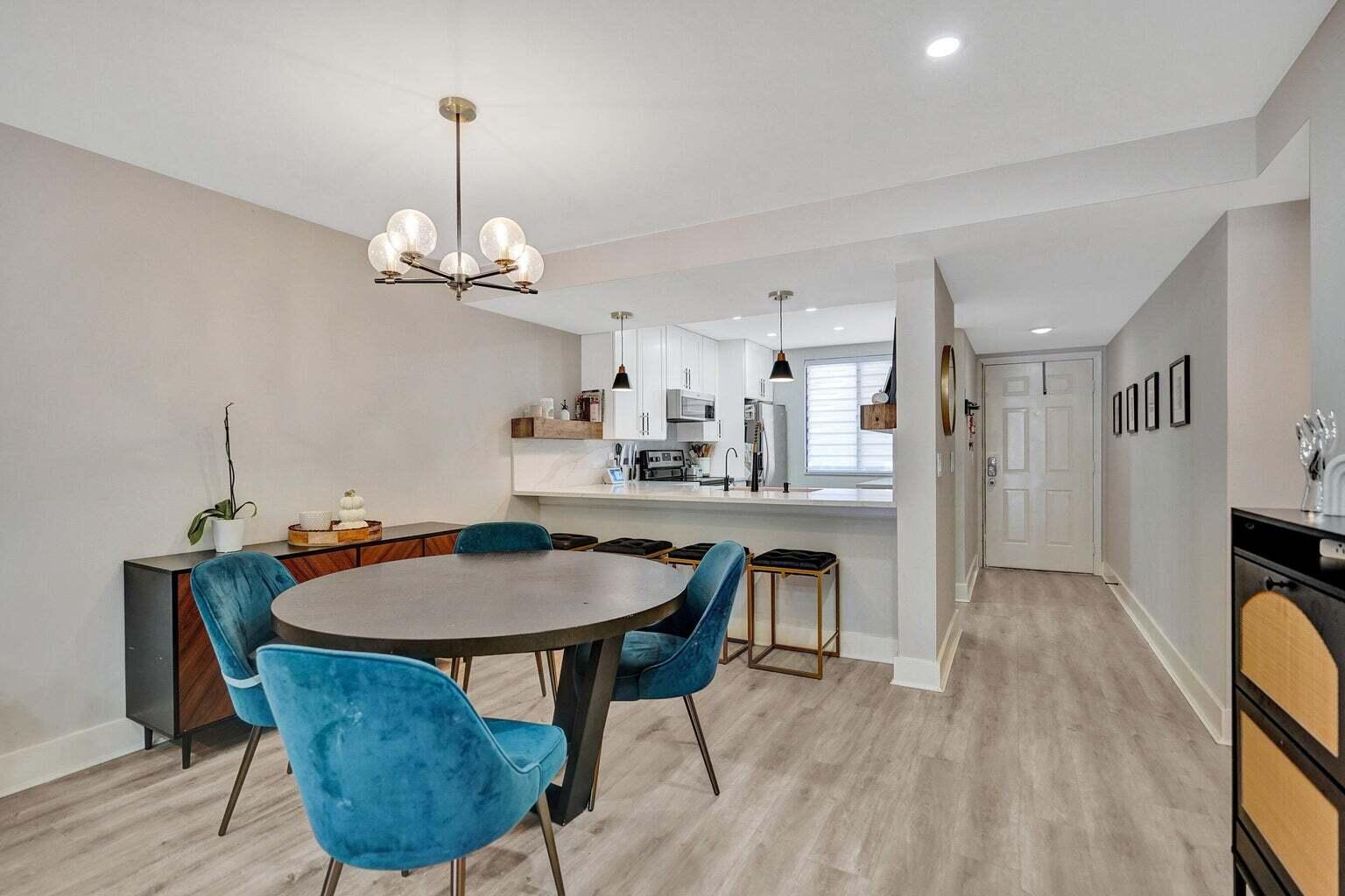 6193 Balboa Circle, Unit 201 Boca Raton, FL 33433 - Photo 16 of 62 a dining room with wooden floor a chandelier a wooden table and chairs