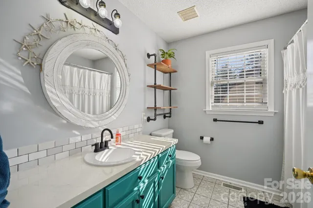 a bathroom with a granite countertop toilet a sink and a mirror