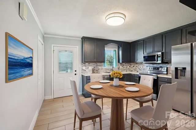 a kitchen with stainless steel appliances granite countertop a dining table chairs and a refrigerator