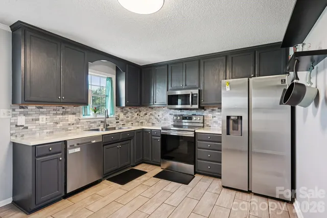 a kitchen with stainless steel appliances granite countertop a sink stove and refrigerator