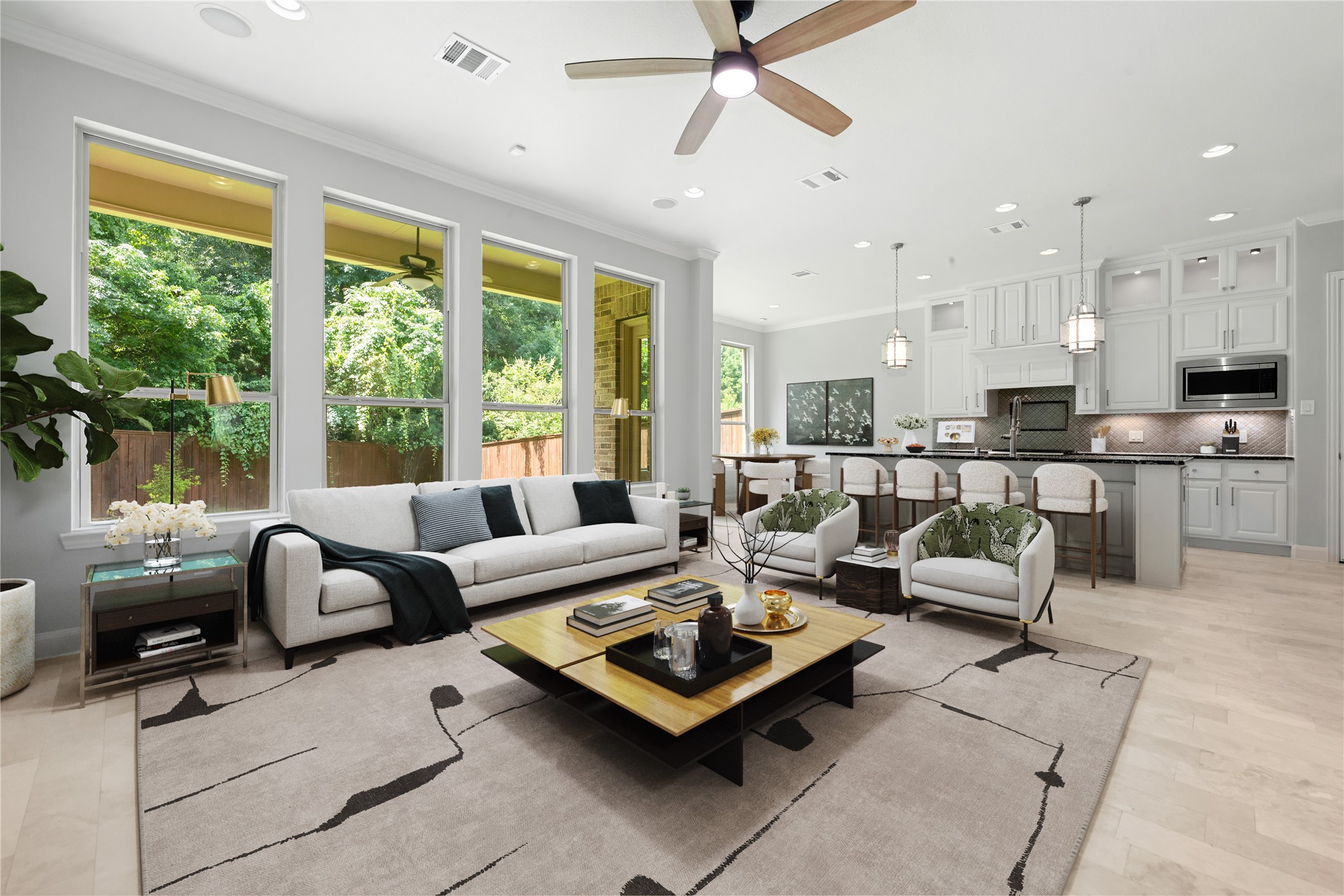 98 Herons Flight Place Spring, TX 77389 - Photo 6 of 29 Bright, open-concept living area filled with natural light from a wall of oversized windows, flowing seamlessly into the gourmet kitchen and dining space. Features soft neutral tones, crown molding, recessed lighting, a modern ceiling fan, and serene wooded views just beyond the glass! *Virtually Staged