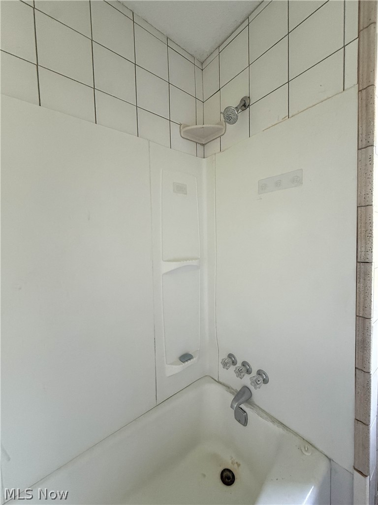 3443 Sheridan Road Youngstown, OH 44502 - Photo 14 of 24 White bathtub with integrated shower surround, featuring a corner shelf and a multi-setting shower head