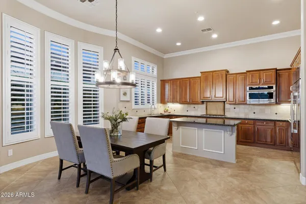 a kitchen with granite countertop a stove a sink a dining table and chairs