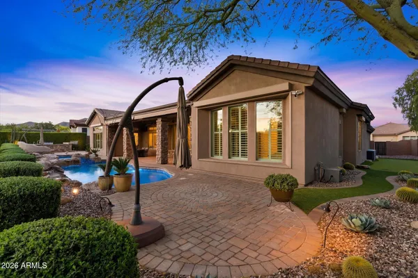a backyard of a house with table and chairs under an umbrella