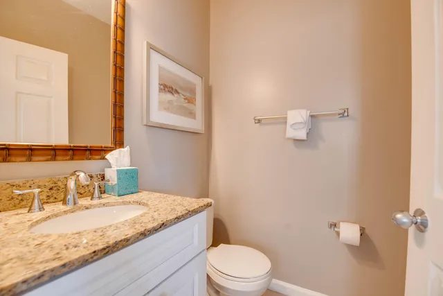 a bathroom with a granite countertop toilet sink and mirror