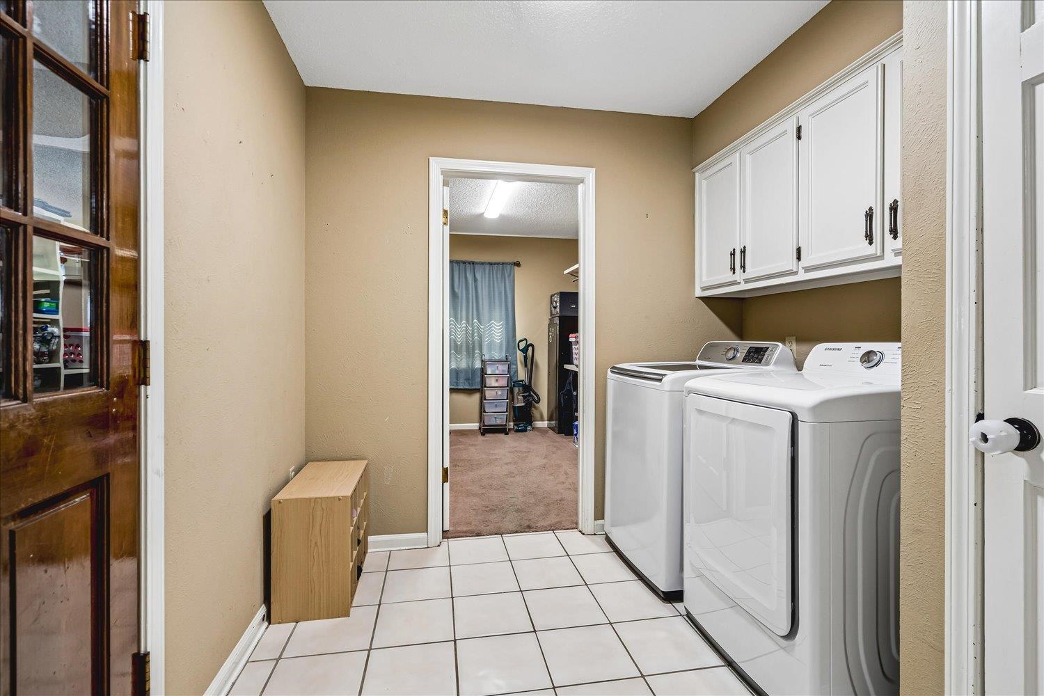 5711 Yale Road Bartlett, TN 38134 - Photo 19 of 29 Utility area featuring white square tile flooring, white upper cabinetry with black hardware, and a wood-finish interior door with glass panes