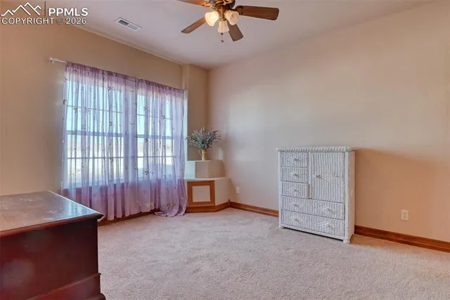 an empty room with chandelier fan and windows