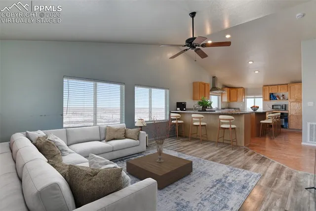 a living room with furniture kitchen view and a large window