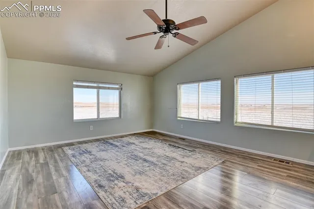 a view of empty room with wooden floor and fan