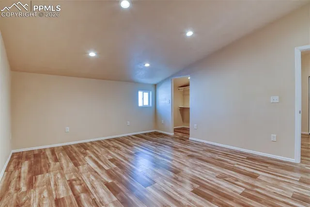 a view of an empty room with wooden floor and window
