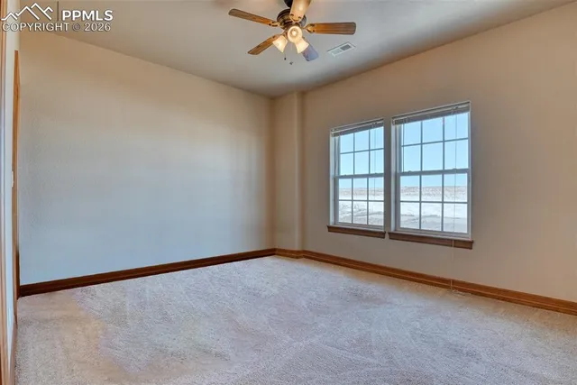 an empty room with chandelier fan and windows