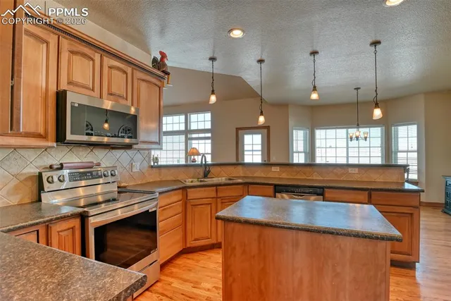 a kitchen with stainless steel appliances granite countertop a sink a stove and a microwave