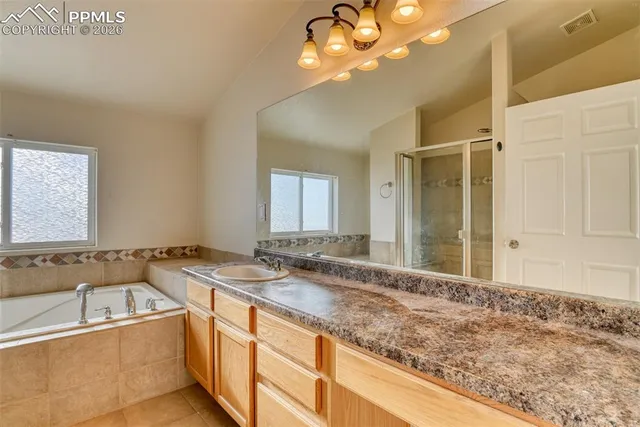 a bathroom with a granite countertop sink a large mirror and a bathtub
