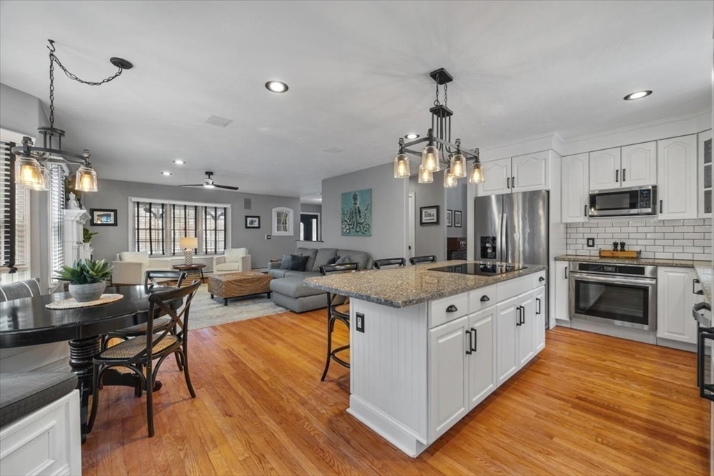 31 Round Hill Road Kingston, MA 02364 - Photo 12 of 42 a large kitchen with kitchen island a dining table chairs and a wooden floor
