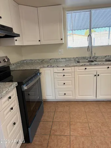 a kitchen with granite countertop white cabinets and window
