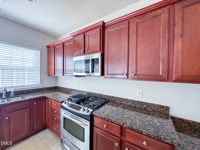 a kitchen with granite countertop a stove top oven sink and cabinets