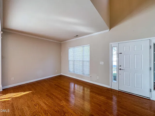 a view of an empty room with wooden floor and window
