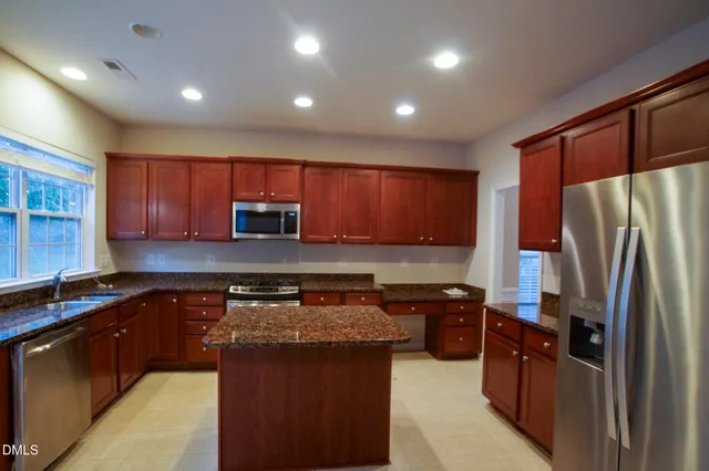 a kitchen with kitchen island granite countertop a refrigerator stove top oven and sink