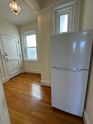 an empty room with wooden floor cabinet and windows