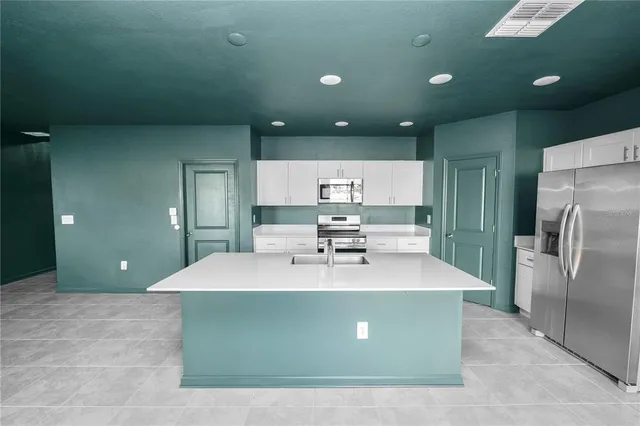 a view of a kitchen with kitchen island a sink stainless steel appliances and cabinets