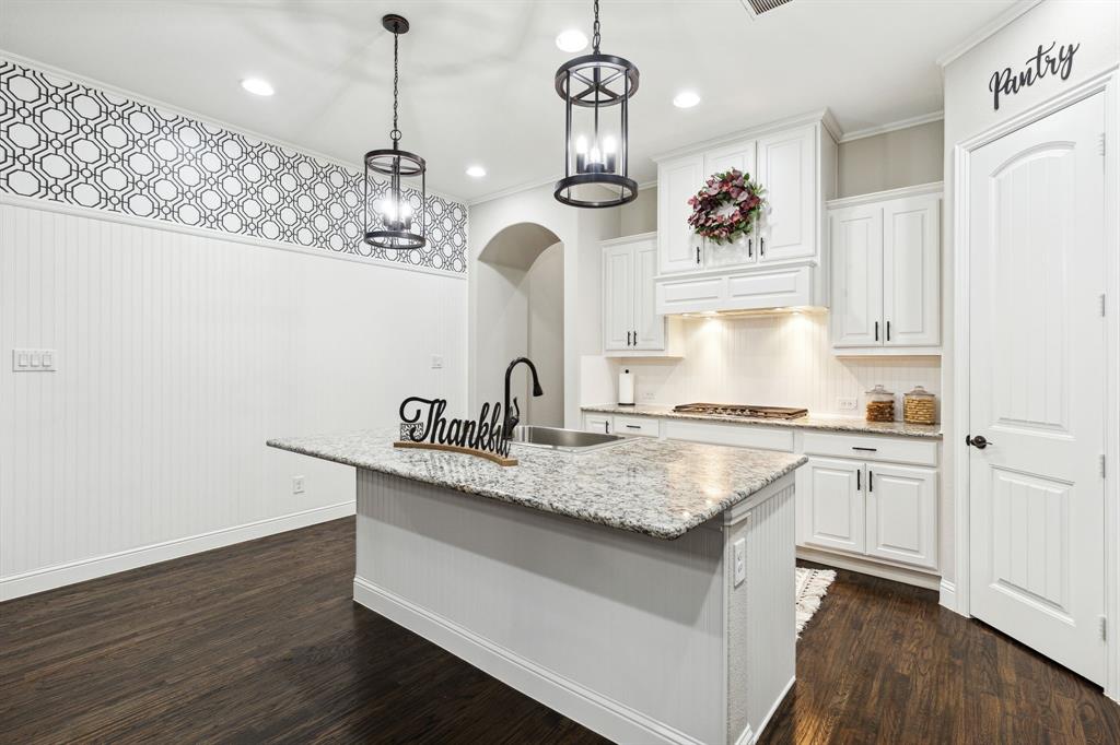 a kitchen with a sink dishwasher and white cabinets with wooden floor