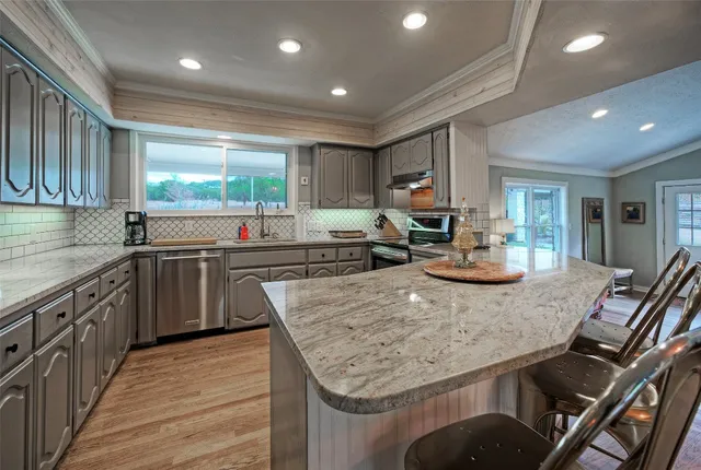 a kitchen with kitchen island granite countertop a sink cabinets and stainless steel appliances