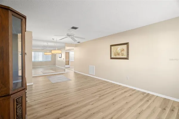 a view of empty room with wooden floor and fan