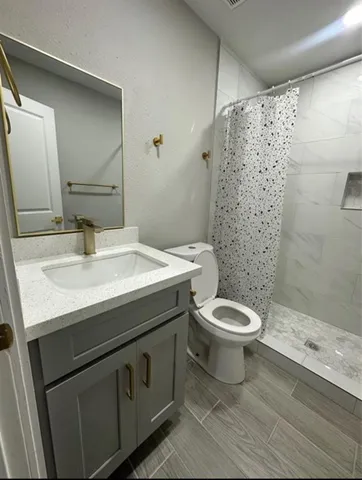 a bathroom with a granite countertop toilet a sink and a mirror
