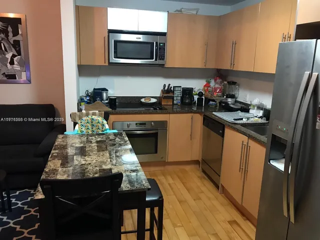 a kitchen with stainless steel appliances a stove a sink a microwave a refrigerator and cabinets