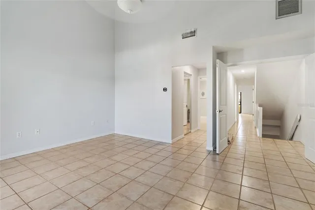a view of an empty room with wooden floor and a ceiling fan