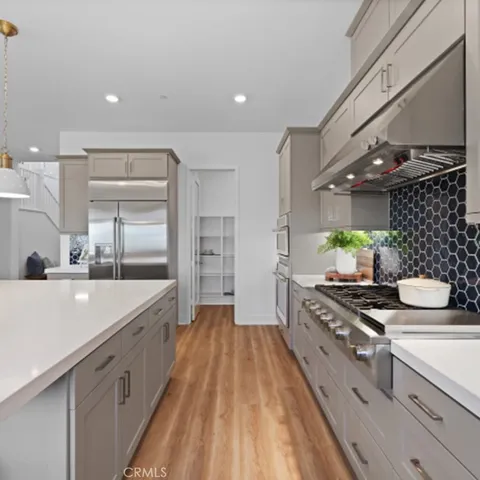a large kitchen with stainless steel appliances a stove a sink and a refrigerator