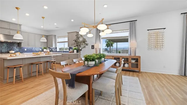 a dining room filled chandelier and wooden floor
