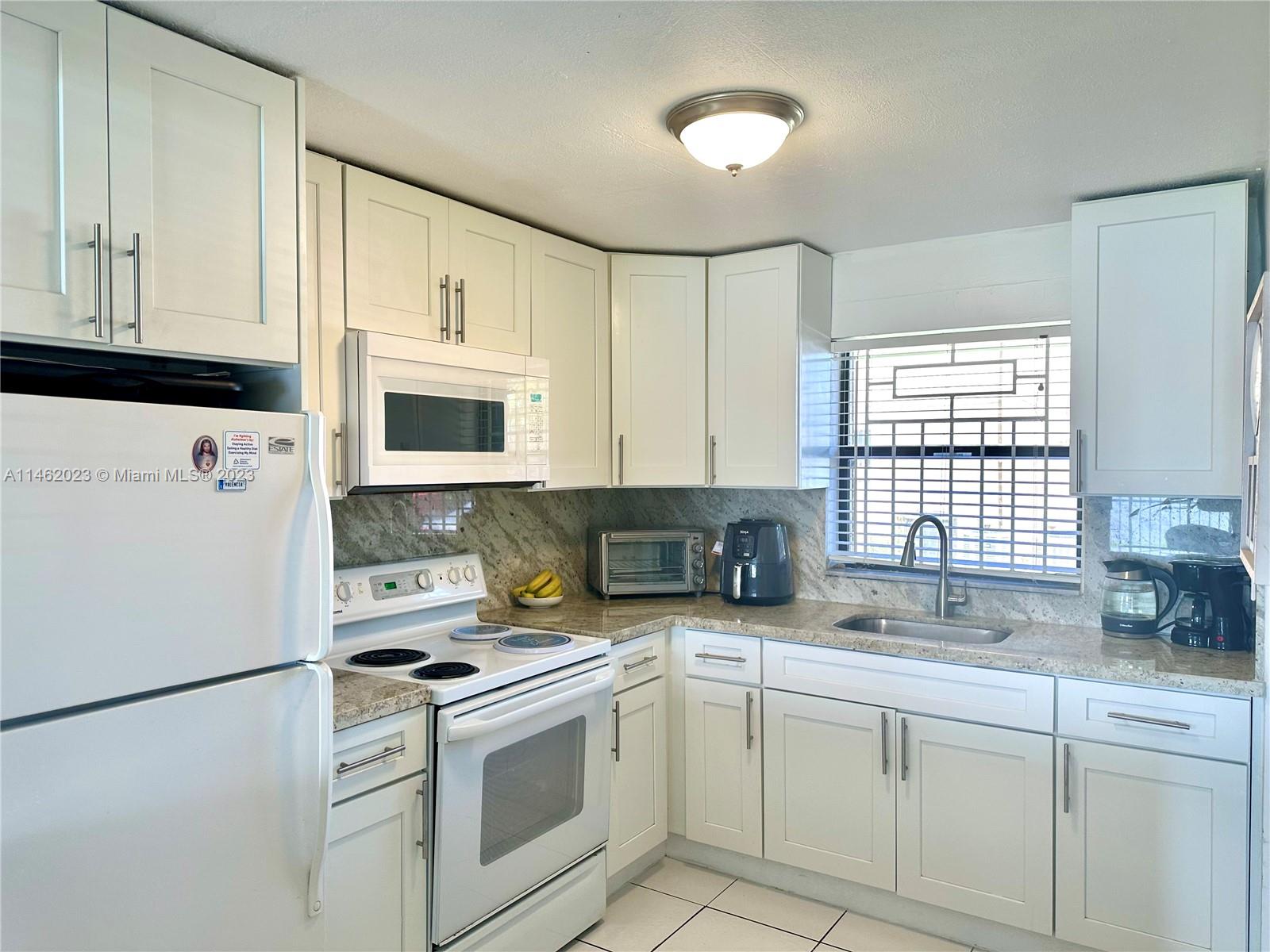 2580 West 67th Place, Unit 1011 Hialeah, FL 33016 - Photo 4 of 23 a kitchen with white cabinets and white appliances