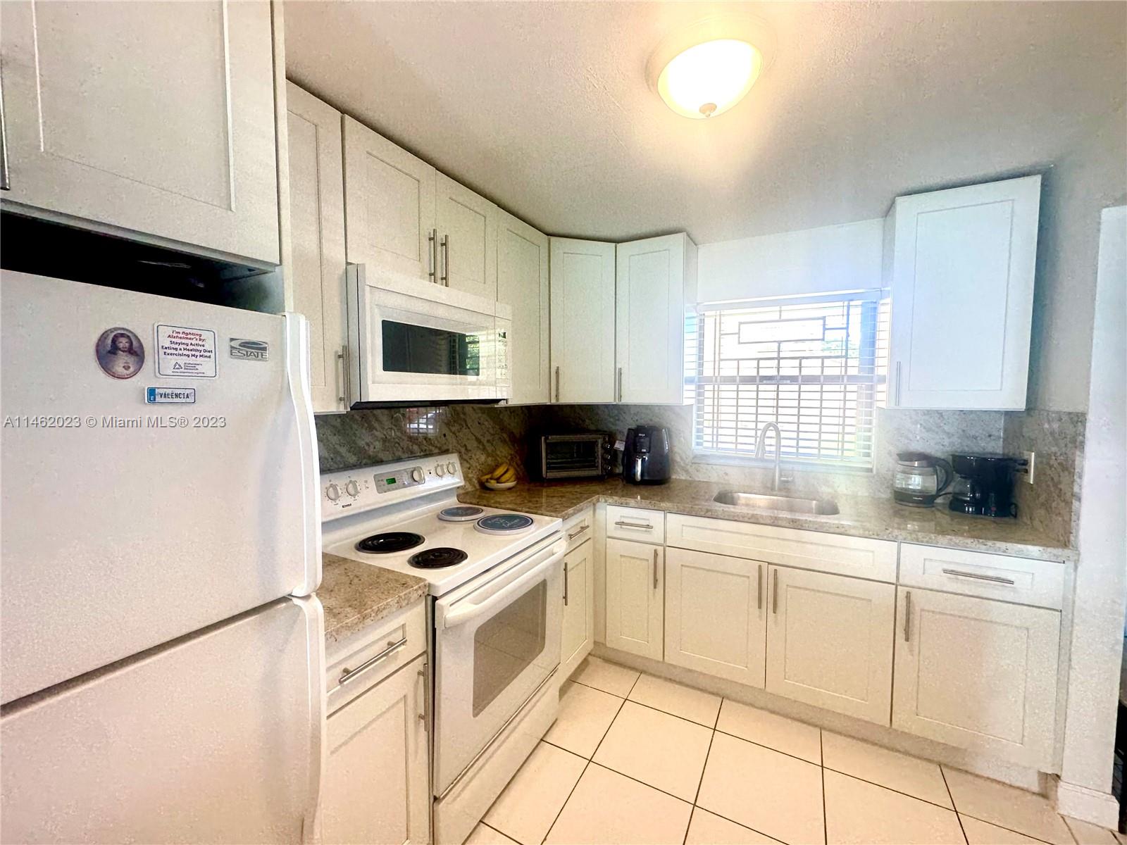2580 West 67th Place, Unit 1011 Hialeah, FL 33016 - Photo 6 of 23 a kitchen with white cabinets sink and white appliances