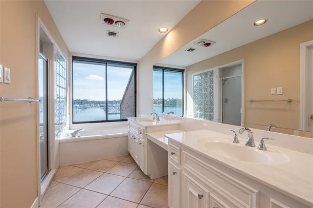 a spacious bathroom with a tub sink double vanity and mirror