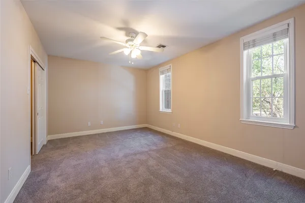 an empty room with windows and fan