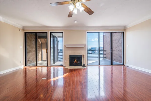 a view of an empty room with wooden floor fireplace and a window