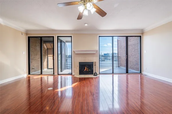 a view of an empty room with wooden floor fireplace and a window