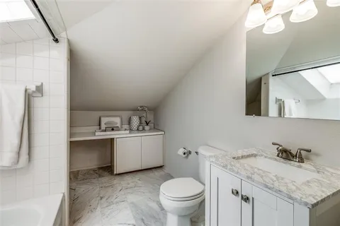 a bathroom with a granite countertop sink a toilet and a mirror