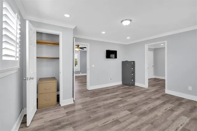a view of an empty room with wooden floor and windows