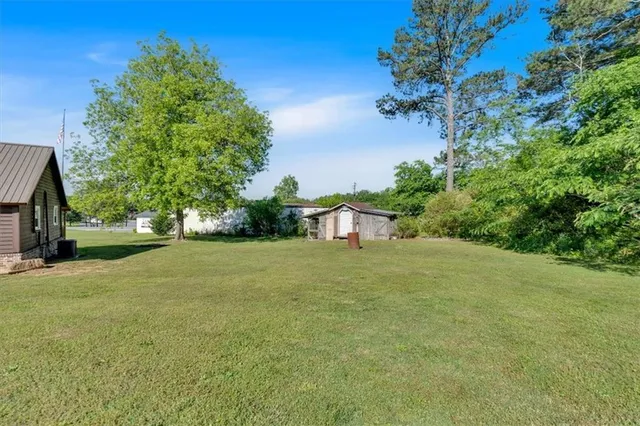 a tall yellow house with a big yard plants and trees all around